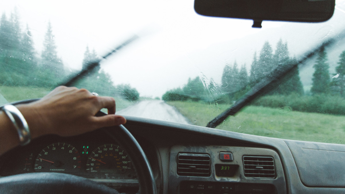 cambiar las escobillas limpiaparabrisas: imagen decorativa que muestra el interior de un coche circulando bajo la lluvia con el cristal lleno de agua